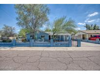 Charming light blue exterior with a tidy front yard and secure decorative metal and concrete fence at 2335 W Campus Dr, Phoenix, AZ 85015
