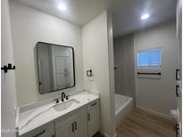 The bathroom is equipped with black hardware, white cabinets, and a modern shower-tub combo at 5635 S 11Th Dr, Phoenix, AZ 85041