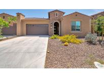 Charming single-story home featuring a desert landscape, arched entry and a two car garage with a tile roof at 16935 W Sheridan St, Goodyear, AZ 85395