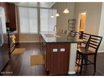Open kitchen featuring a breakfast bar with seating, stainless steel appliances, and dark wood cabinetry at 6605 N 93Rd Ave # 1071, Glendale, AZ 85305