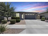 Charming single-story home featuring a paved driveway, landscaped front yard, and attached two-car garage at 14393 W Wethersfield Rd, Surprise, AZ 85379
