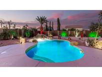 Inviting backyard pool with rock waterfall and lush desert landscaping highlighted by colorful sunset at 31453 N Blackfoot Dr, San Tan Valley, AZ 85143