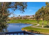 Scenic view of the golf course and a lake with mountain views in the background, framed by trees at 7272 E Gainey Ranch Rd # 23, Scottsdale, AZ 85258