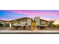 Charming single-story home featuring stone accents, manicured landscaping, and a welcoming illuminated entryway at 13820 W Weaver Ct, Litchfield Park, AZ 85340