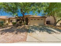 Inviting front exterior with mature shade trees, two-car garage, and desert landscaping at 15460 W Mescal W St, Surprise, AZ 85379