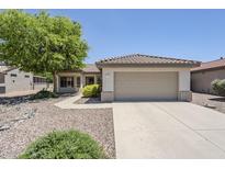 Charming single-story home features a neutral facade, tiled roof, 2-car garage, and mature landscaping at 15960 W Indigo Ln, Surprise, AZ 85374