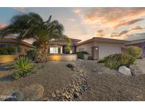 Inviting desert-landscaped front yard with a stately palm tree and a charming rock-lined dry creek bed at 16857 W Villagio Dr, Surprise, AZ 85387