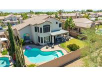 A relaxing backyard featuring a pool, covered patio, lush landscaping and a beautiful two-story home at 1694 E Campbell Ave, Gilbert, AZ 85234