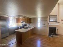 Bright open-concept living room featuring a fireplace, wood floors, and a kitchen with ample counter space at 2020 W Union Hills Dr # 240, Phoenix, AZ 85027