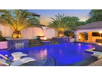 Stunning outdoor pool featuring palm trees, fire bowls, waterfalls, a swim up bar and comfortable lounge chairs at 2985 N Point Ridge Rd, Buckeye, AZ 85396