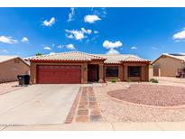 Charming single-story home featuring a red garage door, beautiful desert landscaping, and a white tiled roof at 6302 E Portia St, Mesa, AZ 85215