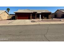 Charming single-story home features a red garage door, tile roof, and desert landscaping at 6302 E Portia St, Mesa, AZ 85215