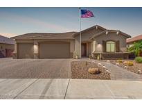Beautiful home with a three car garage, a brick driveway and a manicured, desert landscaped yard at 1036 W Siebold Tree Ave, Queen Creek, AZ 85140