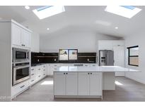 Bright, open kitchen features an expansive island, stainless steel appliances, skylights, and modern black backsplash at 4246 E Mulberry Dr, Phoenix, AZ 85018