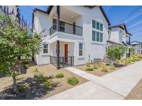 Charming townhome with a red door, black accents, balcony, and manicured landscaping at 11300 N Casa Dega Dr # 1005, Surprise, AZ 85388