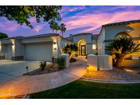 Stunning home exterior featuring an arched entryway, beautiful desert landscaping, and a two-car garage at sunset at 1724 W Blue Ridge Way, Chandler, AZ 85248