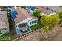 Stunning aerial view of a home featuring a putting green, patio with fire pit, and solar panels for energy efficiency at 20784 W Minnezona Ave, Buckeye, AZ 85396