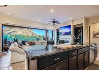 Modern kitchen with dark cabinetry, granite counters, stainless appliances, and mountain views through large windows at 27000 N Alma School Pkwy # 1033, Scottsdale, AZ 85262