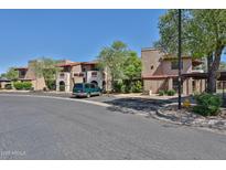 Condominium building with covered parking and mature trees on a sunny day with blue sky at 5757 W Eugie Ave # 2068, Glendale, AZ 85304