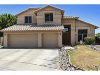 Inviting two-story home boasts a three-car garage, desert landscaping, and a neutral stucco facade under a sunny sky at 5957 W Robin Ln, Glendale, AZ 85310