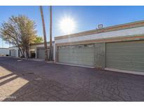 View of well-maintained garages with neutral paint and mature trees under a blue sky at 7132 N 63Rd Dr, Glendale, AZ 85301