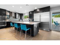 Modern kitchen features dark cabinetry, a large island with seating, and stainless steel appliances at 7533 N 8Th St, Phoenix, AZ 85020
