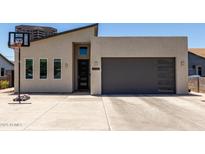 Modern home featuring a contemporary design, gray garage door, and a basketball hoop in the driveway at 1005 E Weldon Ave, Phoenix, AZ 85014