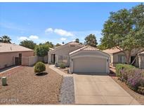 Charming single-Gathering home boasting mature landscaping and a well-maintained two-car garage, set against a clear blue sky at 1703 E Palo Blanco Way, Gilbert, AZ 85296