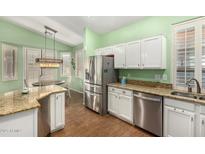Charming kitchen with granite countertops, stainless steel appliances, and wood-style flooring at 18080 W Spencer Dr, Surprise, AZ 85374