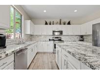 Bright kitchen with granite countertops, stainless steel appliances, and light wood-look flooring at 4976 E Thunderbird Dr, Chandler, AZ 85249
