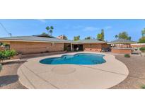 Inviting in-ground pool with a circular lounge area surrounded by lush landscaping and a brick home at 524 W Sunset Cir, Mesa, AZ 85201