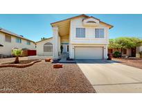 Inviting two-story home featuring a spacious driveway, desert landscaping, and a charming front porch entrance at 8541 W Pershing Ave, Peoria, AZ 85381