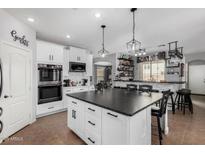 Bright kitchen with white cabinets, a large island with a black countertop, and a bar area at 12601 W San Miguel Ave, Litchfield Park, AZ 85340