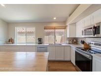 Bright kitchen featuring wood-top island and white cabinets at 15128 W Melissa Ln, Surprise, AZ 85374