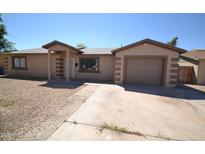 Cozy single-story home showcasing a desert landscape, attached garage, and covered porch entryway at 2036 N 64Th Ln, Phoenix, AZ 85035