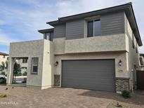 New two-story home featuring a gray garage door, stacked stone accents, and a stucco finish at 3354 S 180Th Ln, Goodyear, AZ 85338
