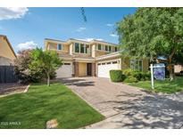 Charming two-story home featuring a paver driveway, lush landscaping, and a three-car garage at 4109 E Sierra Madre Ave, Gilbert, AZ 85296