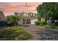 Charming two-story home featuring a paver driveway, lush landscaping, and a three-car garage at 4109 E Sierra Madre Ave, Gilbert, AZ 85296