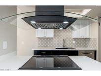 Close-up of the kitchen featuring sleek black vent hood, modern backsplash, and stainless steel appliances at 4228 N 81St St, Scottsdale, AZ 85251