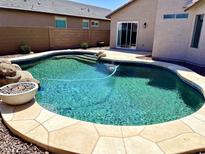 Backyard pool with rock waterfall, stone border, and outdoor fire pit for relaxing and entertaining at 5749 S 247Th Dr, Buckeye, AZ 85326