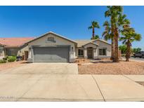 Charming single-story home with a gray two-car garage, desert landscaping, and mature palm trees at 7924 W Hammond Ln, Phoenix, AZ 85043
