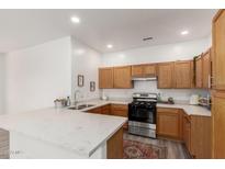 A bright kitchen features wooden cabinetry, quartz countertops, and stainless steel appliances at 11182 W Coronado Rd, Avondale, AZ 85392