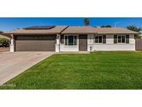 Charming single-story home with a well-manicured lawn and a two-car garage, complemented by solar panels at 1906 N Evergreen St, Chandler, AZ 85225