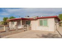 View of the exterior with a concrete driveway, brick and white iron fence, windows, and a front porch at 3622 W Sunland Ave, Phoenix, AZ 85041