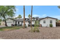 Beautifully renovated home featuring a white painted exterior, dark trim, and mature landscaping at 5612 E Emile Zola Ave, Scottsdale, AZ 85254