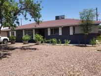 Charming single-story home with gray paint, red roof, well-manicured landscaping, and rock ground cover at 6011 N 33Rd Ave, Phoenix, AZ 85017