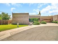 Suburban home with a brick facade, green lawn, attached garage, and mature landscaping, offering a blend of classic and modern design at 7037 N 11Th Dr, Phoenix, AZ 85021