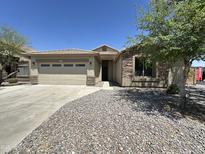 Charming single story home featuring a two-car garage, desert landscaping, and stone accents at 7419 S 45Th Ave, Laveen, AZ 85339