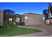 Charming single-story home featuring a well-manicured lawn, two-car garage, and inviting exterior lighting at 7596 N Via De La Siesta --, Scottsdale, AZ 85258