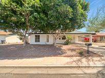 The front of this home features trees, shrubbery and an awning at 920 E Garnet Ave, Mesa, AZ 85204